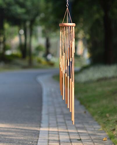 Bamboo wind chimes hanging outdoors near a path.