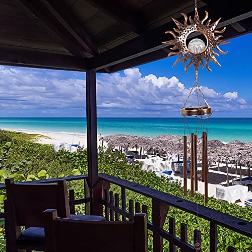 Scenic view from a porch overlooking a beach with chairs, wind chime, and ocean.