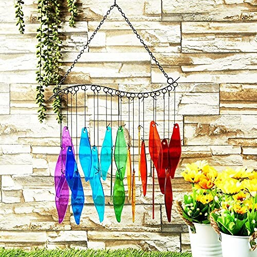 Colorful glass wind chime with leaves against a stone wall with plants