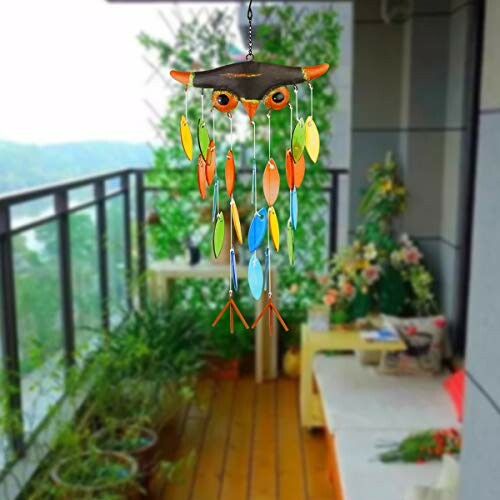 Colorful owl-shaped wind chime hanging on a balcony.