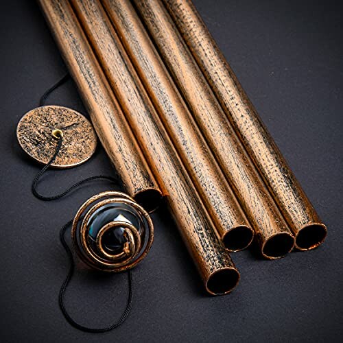 Copper pipes with a decorative pendant on a dark background.