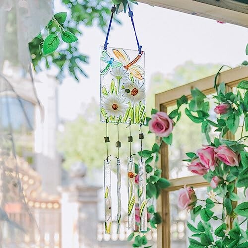 Glass wind chime with floral design hanging near roses.