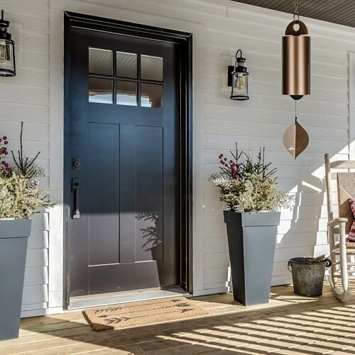 Modern front porch with black door, planters, and rocking chair.