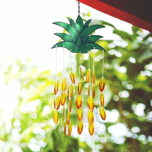 Pineapple-shaped wind chime with hanging yellow ornaments.