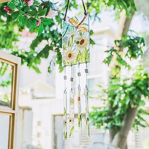 Colorful stained glass wind chime with butterfly and flowers hanging outdoors.