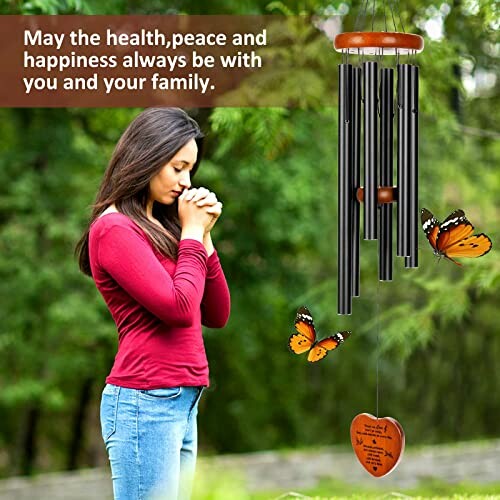 Woman praying outdoors near wind chimes and butterflies.