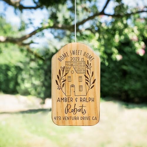 Personalized wooden home sign with names and address hanging outdoors.